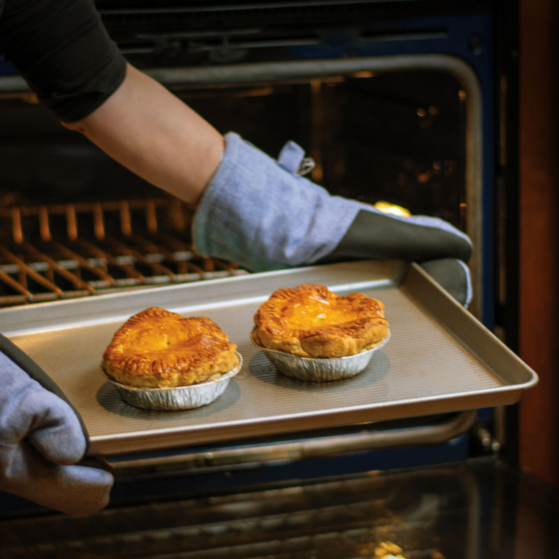 Cooked pot pies getting pulled from the oven