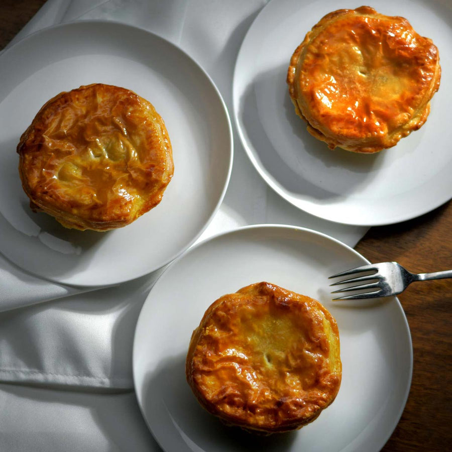 Three cooked puff pastry pot pies on dinner table