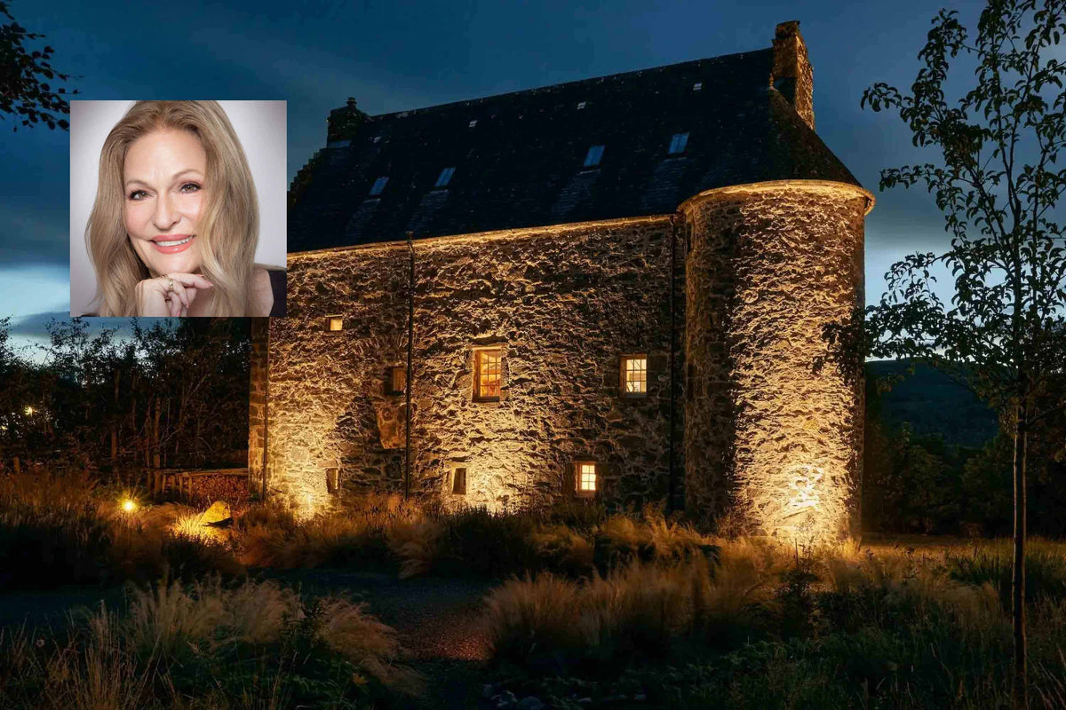 A Scottish stone castle illuminated at night with warm light from the windows, surrounded by grassy landscaping. A small inset portrait of Regina Meredith appears in the upper left corner.