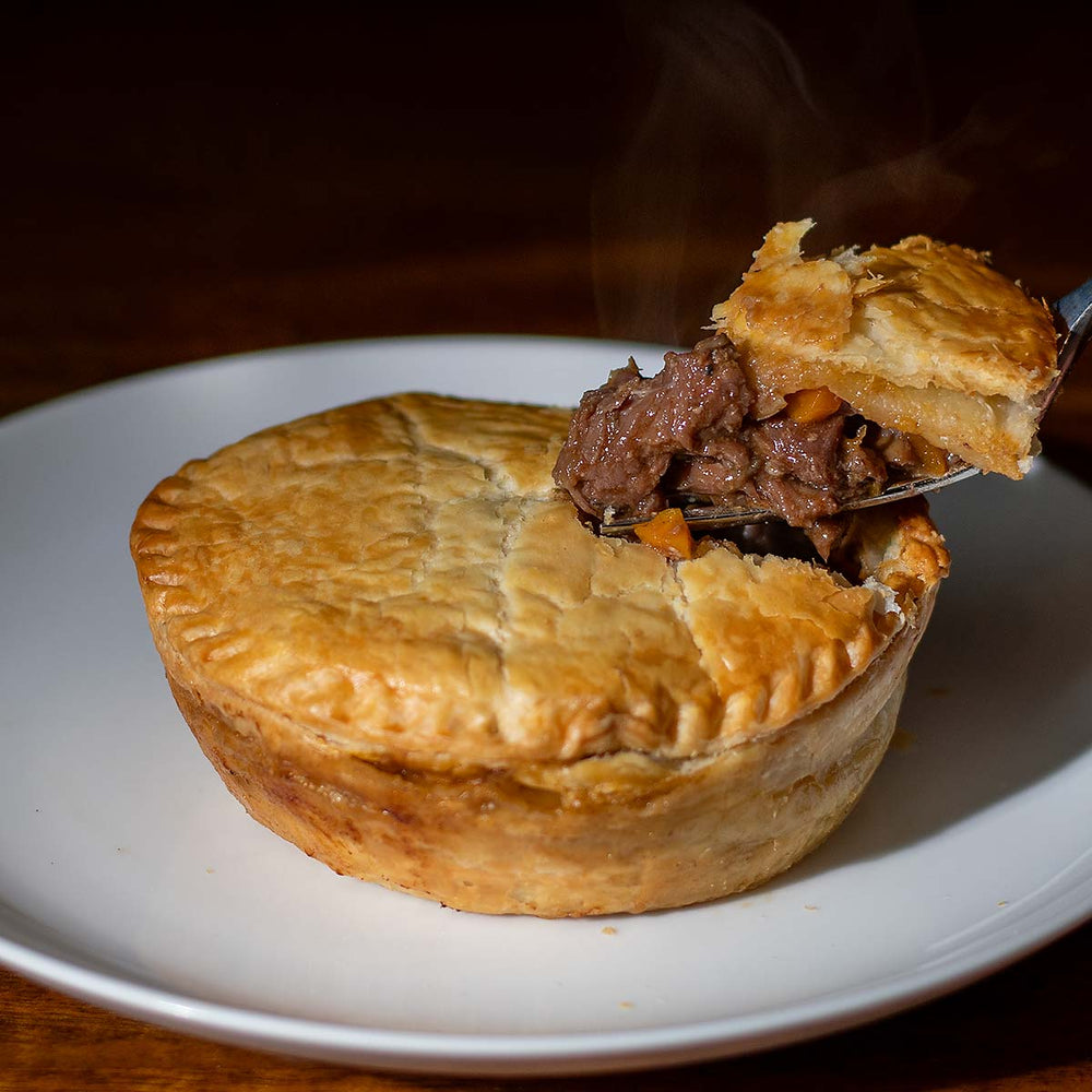 Steaming steak pot pie with a fork on a plate