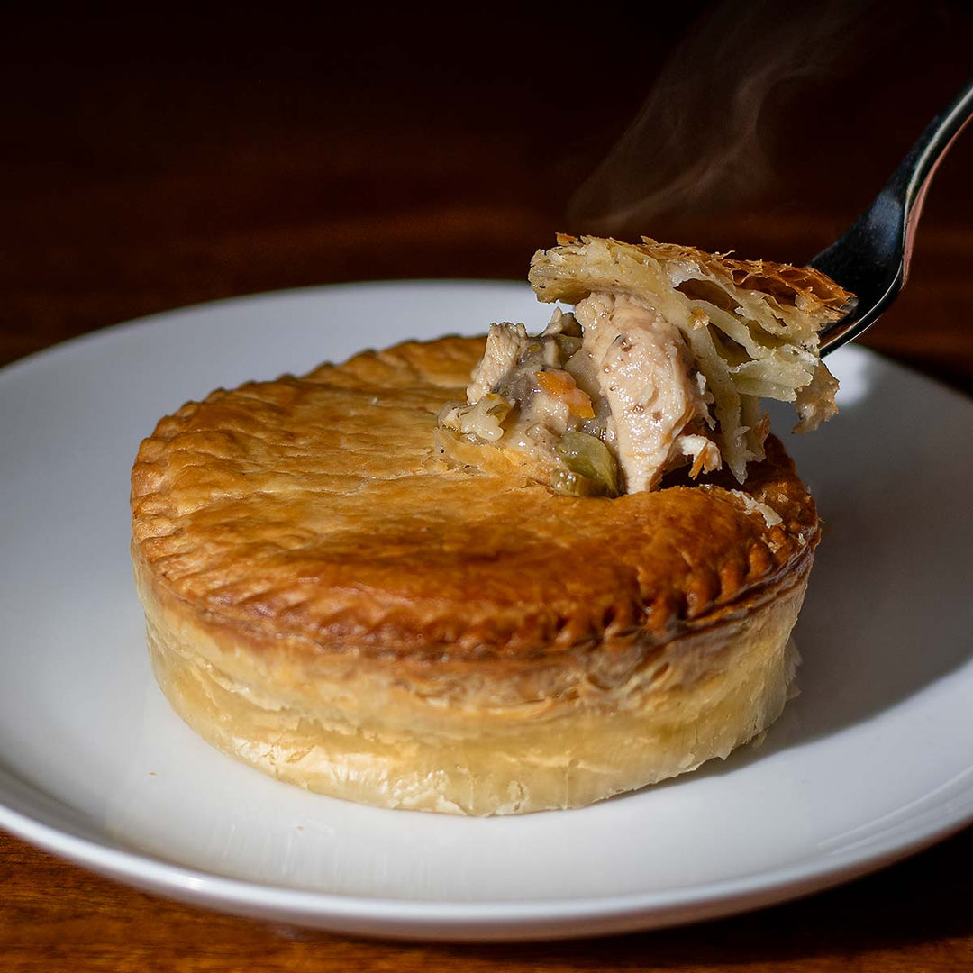 Steaming chicken pot pie with a fork on a plate